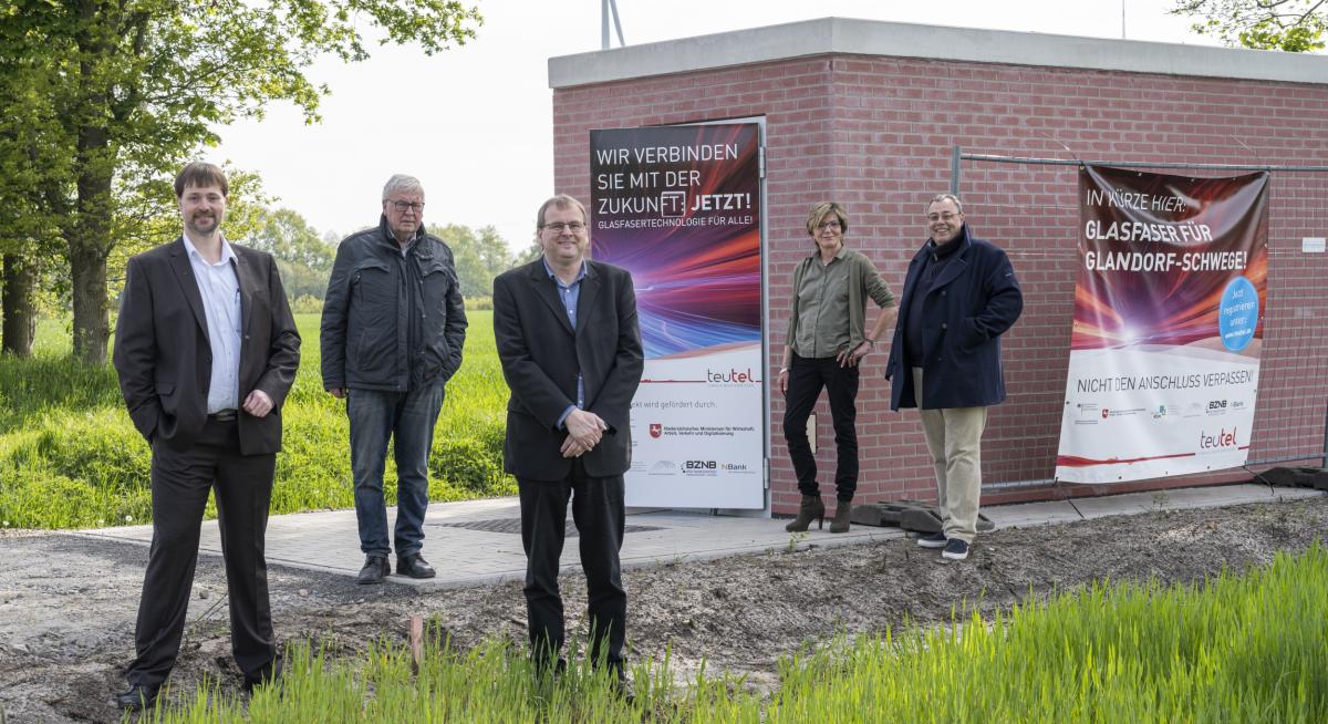 Fünf Personen stehen vor einer Breitband-Internet-Schaltzentrale (POP-Station).