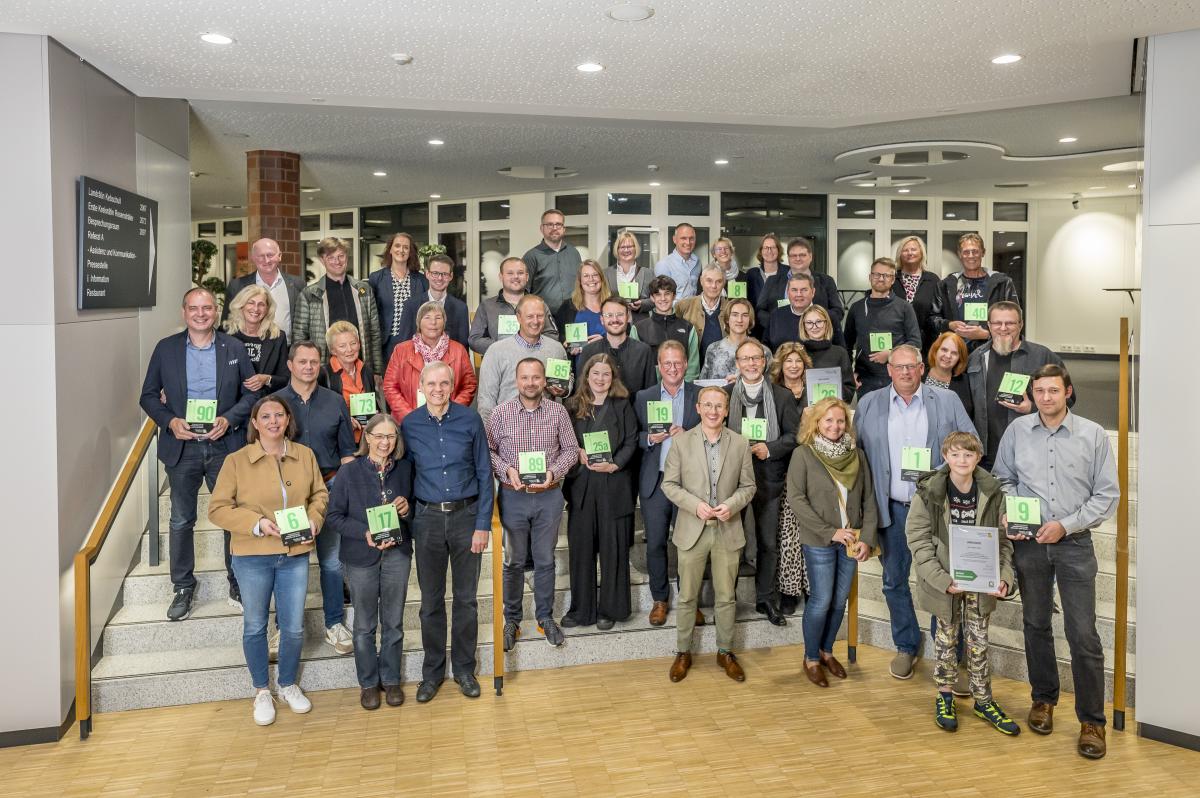 Eine Personengruppe steht auf einer Treppe im Foyer eines Gebäudes.