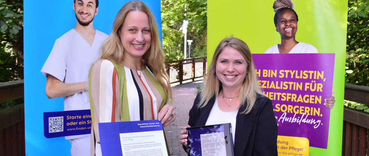 Zwei Personen stehen vor zwei Werbe-Plakaten