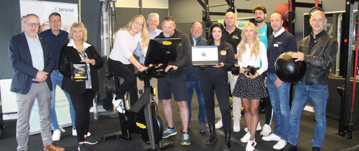 Eine Personengruppe steht in einem Fitnessstudio.