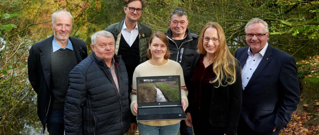 Eine Personengruppe steht vor einem kleinen See