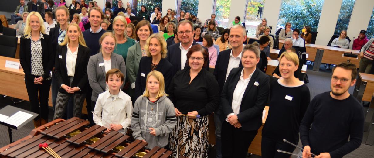 Eine Personengruppe steht in einem Koferenzsaal.