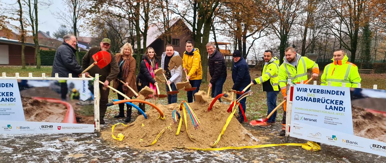 Gruppe von Menschen mit Schaufeln starten symbolisch den Breitbandausbau