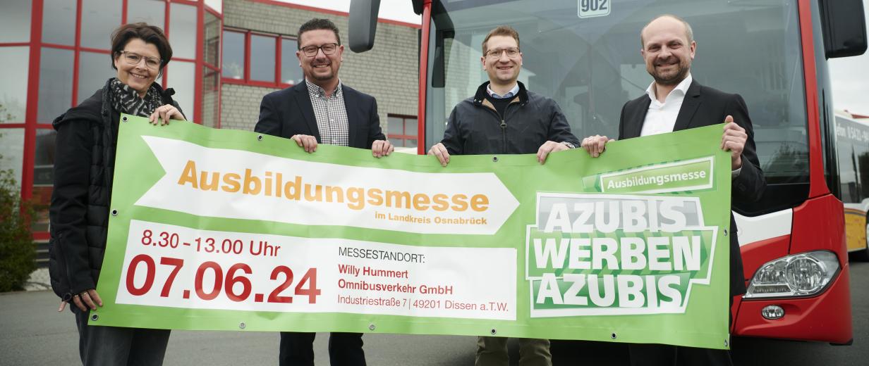 Vier Personen mit einem Banner in den Händen stehen vor einem Linienbus.