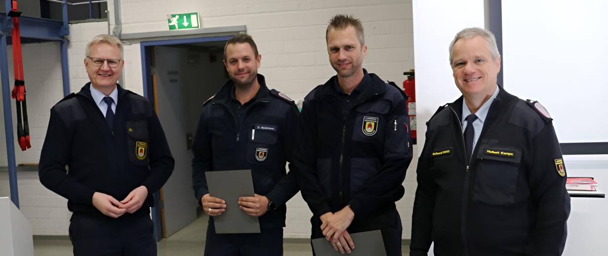 Vier Personen in Uniform stehen in einer Halle.