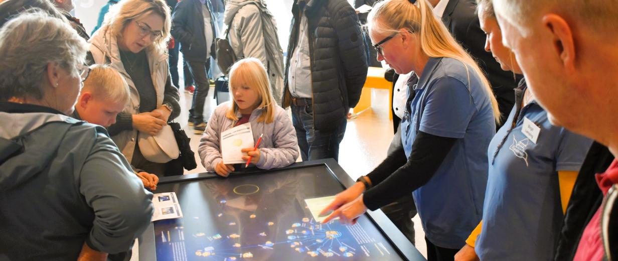 Eine Personengruppe steht um einen Display-Tisch herum.