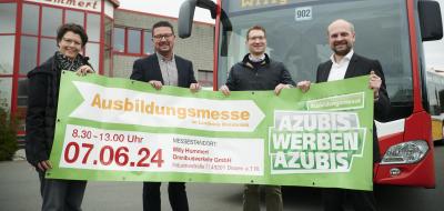 Vier Personen mit einem Banner in den Händen stehen vor einem Linienbus.