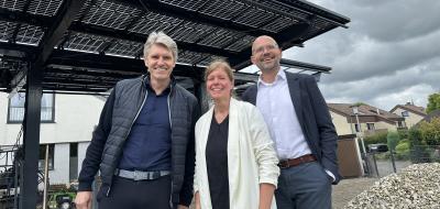 Drei Personen stehen vor einem Solarcarport.