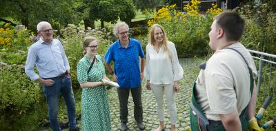 Fünf Personen stehen in einem Garten.