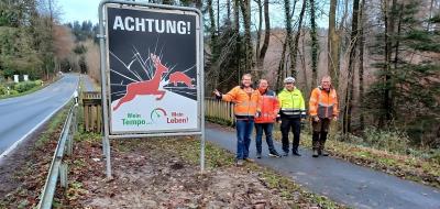 Vier Personen stehen neben einem Warnschild Wildwechsel