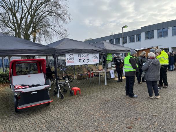 Personen mit neongelben Warnwesten vor einem Infostand