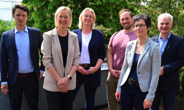 Sechs Personen stehen auf einer Terrasse und schauen in die Kamera.