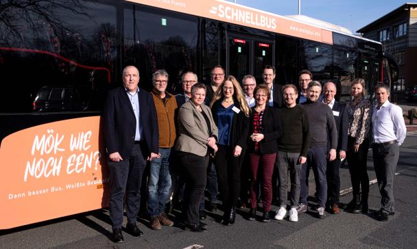 Eine Personengruppe steht vor einem Linienbus.