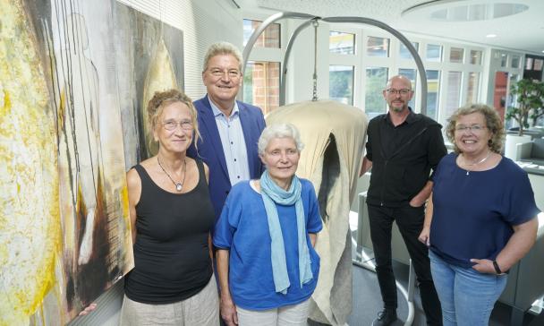 5 Personen vor Ausstellungsbildern