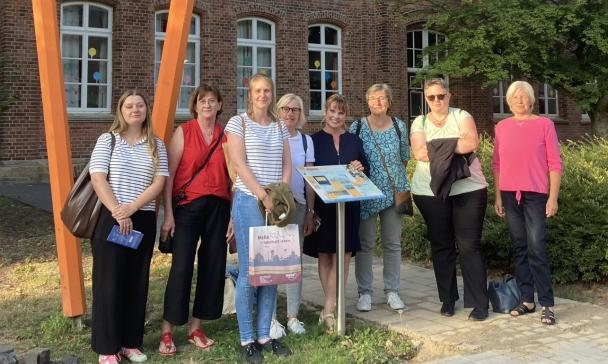 Eine Personengruppe steht vor einem Backsteingebäude.