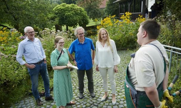 Fünf Personen stehen in einem Garten.