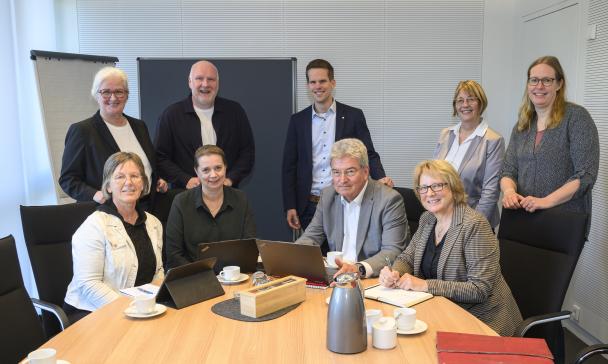 9 Personen vor einem Tisch