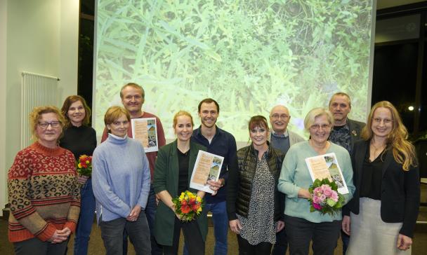 Eine Personengruppe steht vor einer Videoprojektionswand.